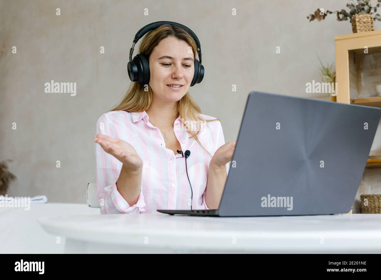 Impegnato in formazione a distanza. Una giovane donna attiva che lavora a distanza partecipa a una riunione virtuale utilizzando un computer di casa. La studentessa partecipa al video co Foto Stock