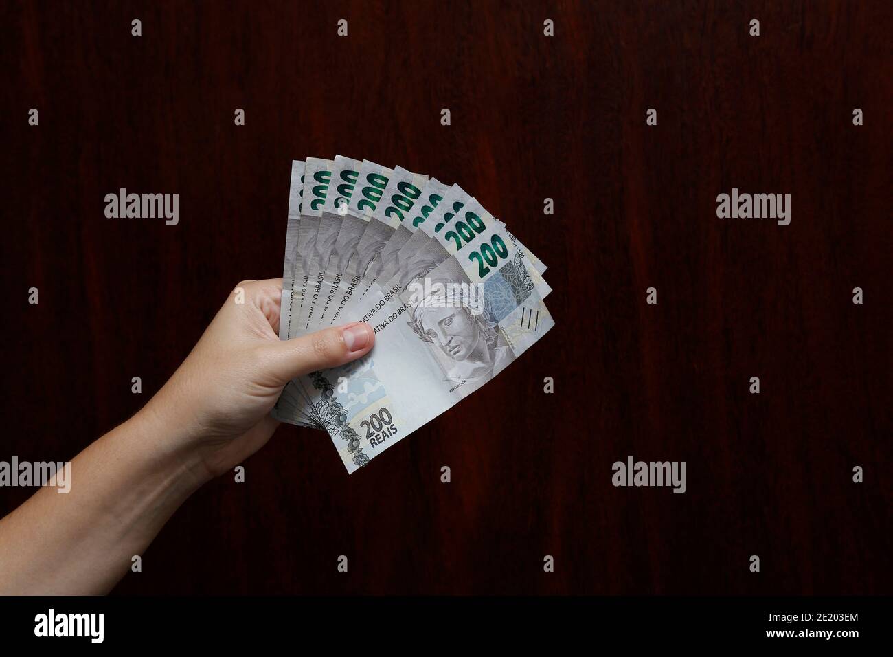 Mani in possesso di banconote reali brasiliane, banconote BRL Brasile, valuta brasiliana, economia e business. Foto Stock