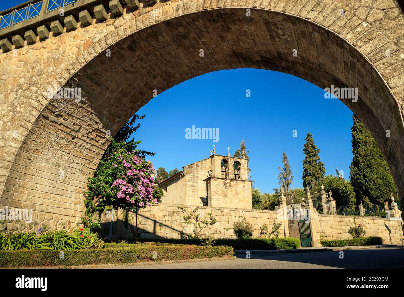 Vouzela Chiesa Madre incorniciata dall'arco del ponte ferroviario a Vouzela, Portogallo, in una giornata di sole. Foto Stock