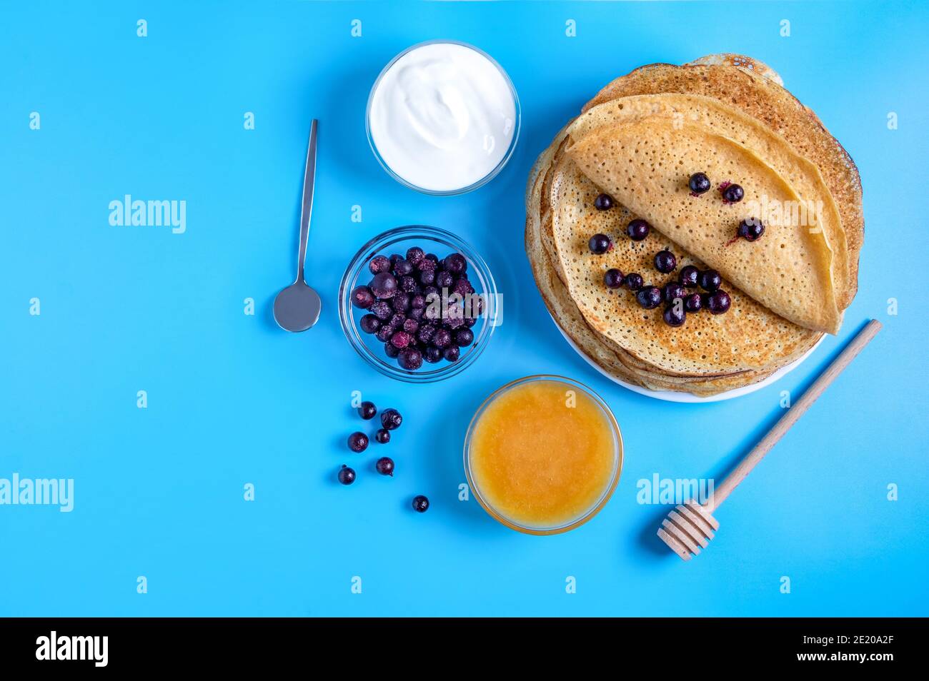 Vista ravvicinata della cucina nazionale russa e dei pancake da dessert con panna acida, frutti di bosco e miele. Piatto tradizionale per la Shrovetide. Focu selettivo Foto Stock