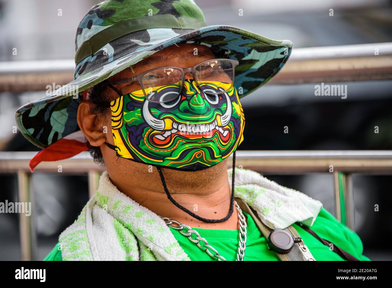 Bangkok, Thailandia - 14 novembre 2020: Un venditore di lotterie posa sorridendo dietro la maschera mistica creatura sorridente stampata per proteggerlo da Covid-19. Foto Stock