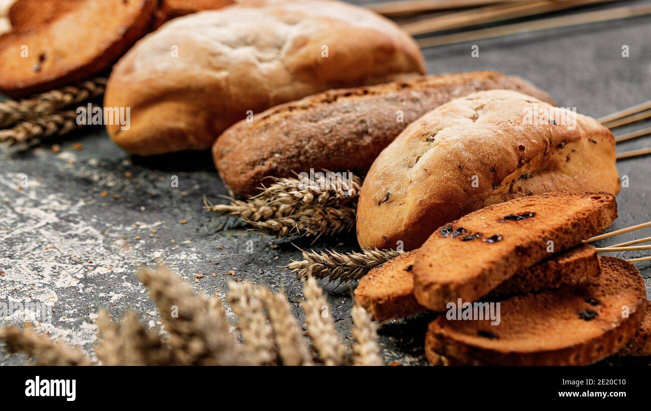 Primo piano di pane tradizionale italiano e dolci su sfondo grigio in cemento. Cantucci, ciabatta. Cucina mediterranea nazionale. Messa a fuoco selettiva Foto Stock