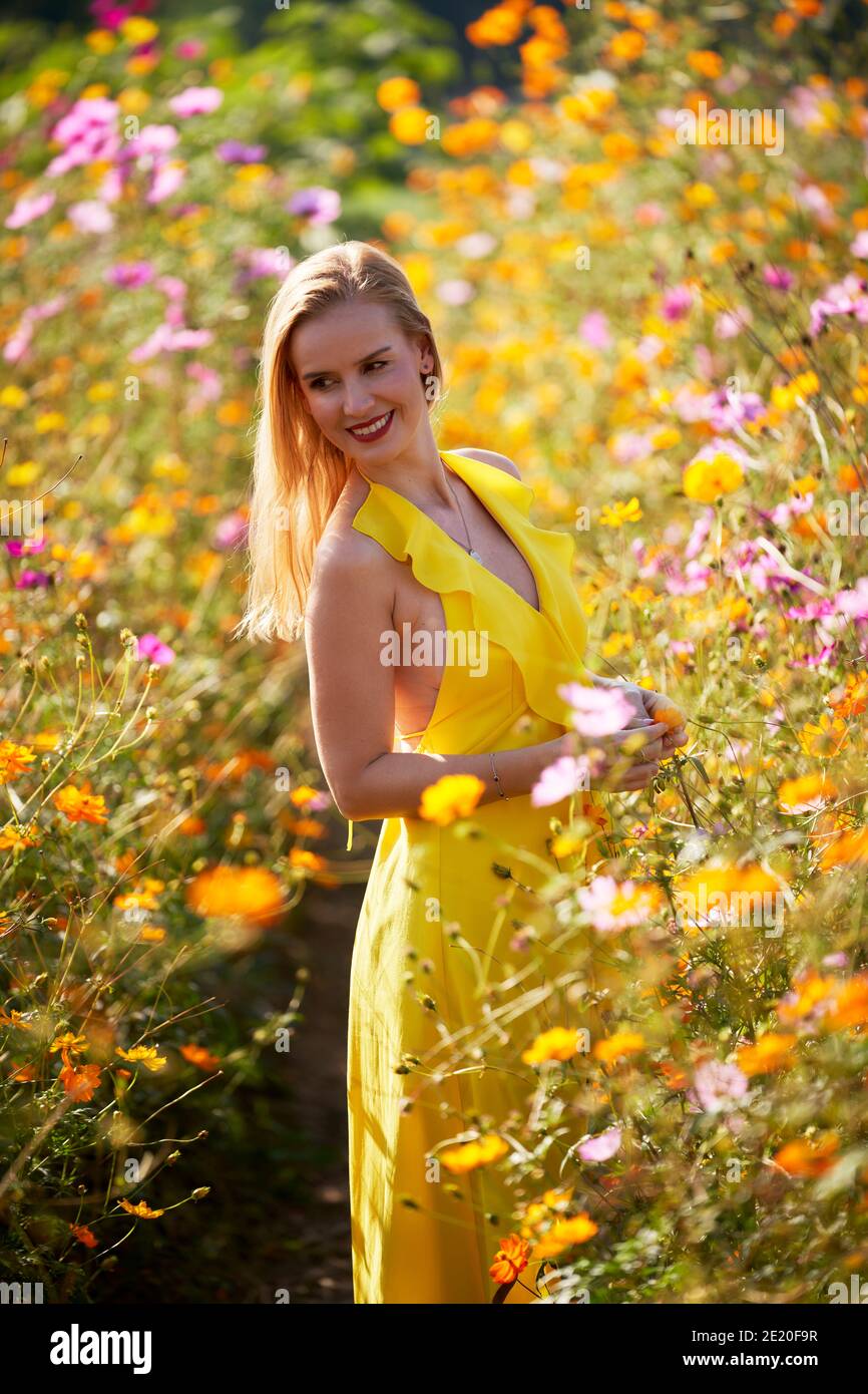 Un bel modello retroilluminato dal sole in un campo pieno di fiori. Foto Stock