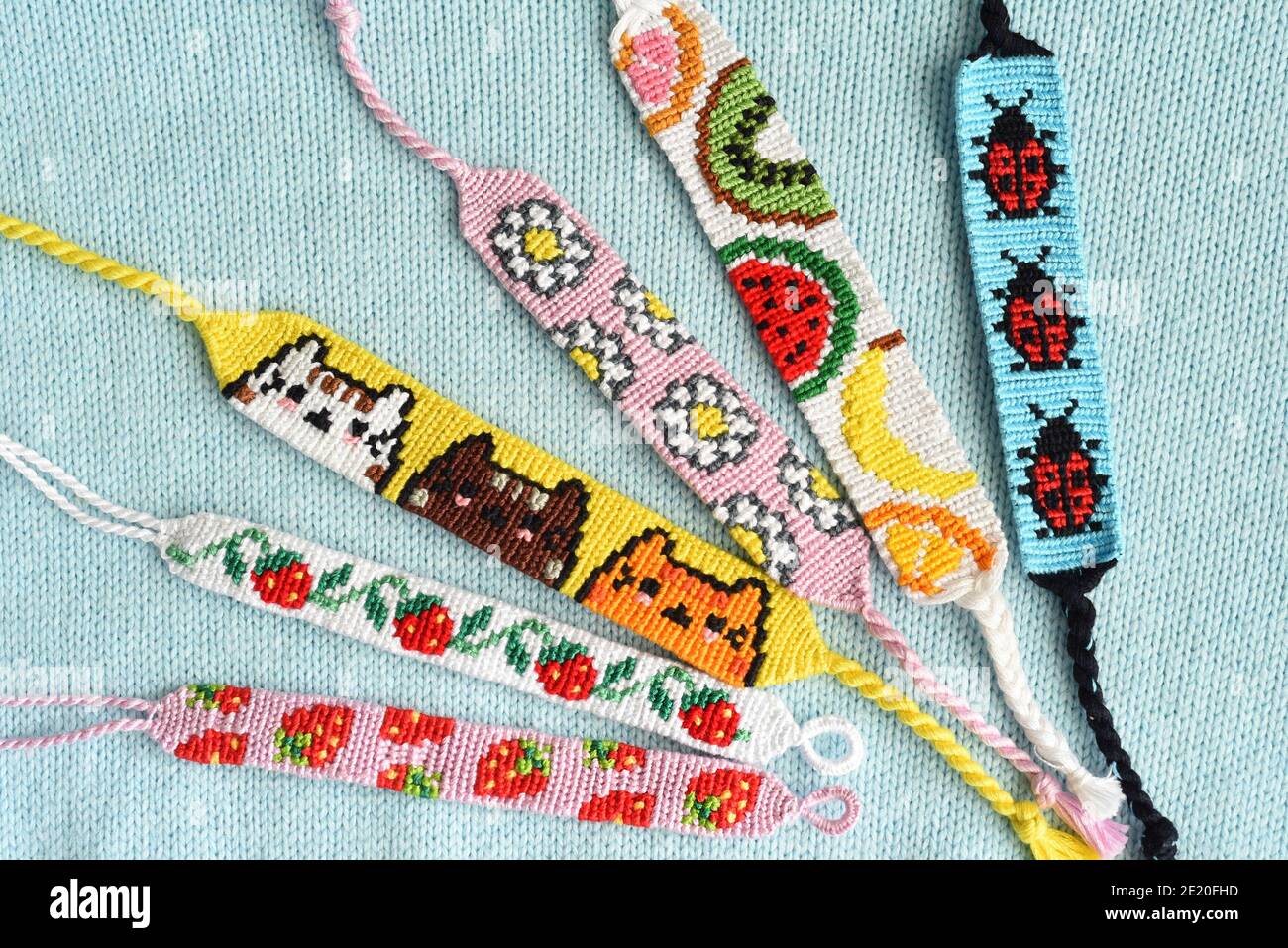 Bracciali di amicizia fai da te con motivo alfa fragola su sfondo tessuto Foto Stock