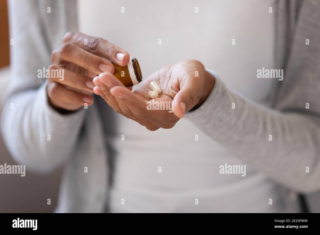 Primo piano giovane donna etnia africana versando pillole da bottiglia. Foto Stock
