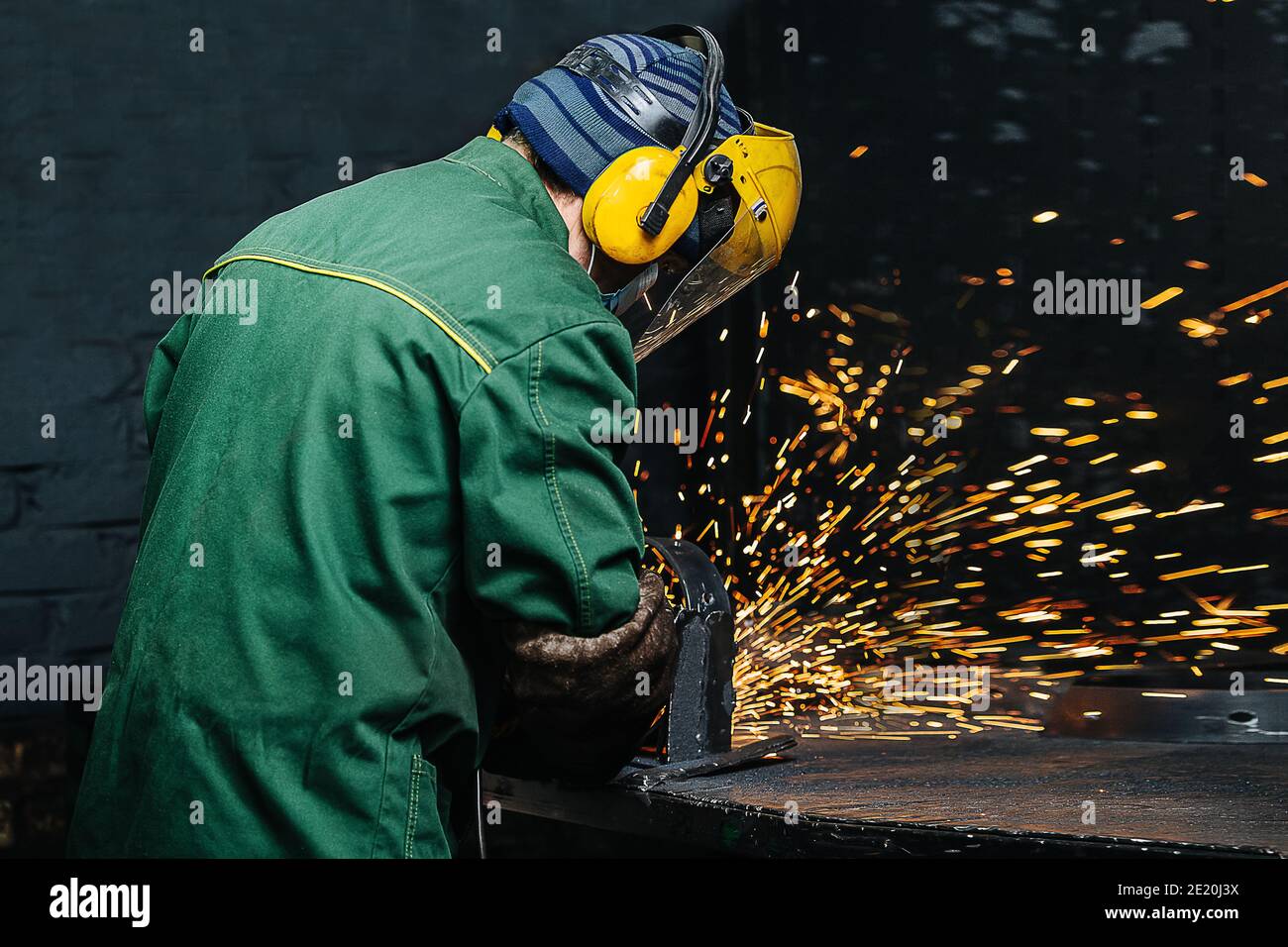Un uomo che lavora con cuciture saldate con una smerigliatrice angolare. Foto Stock