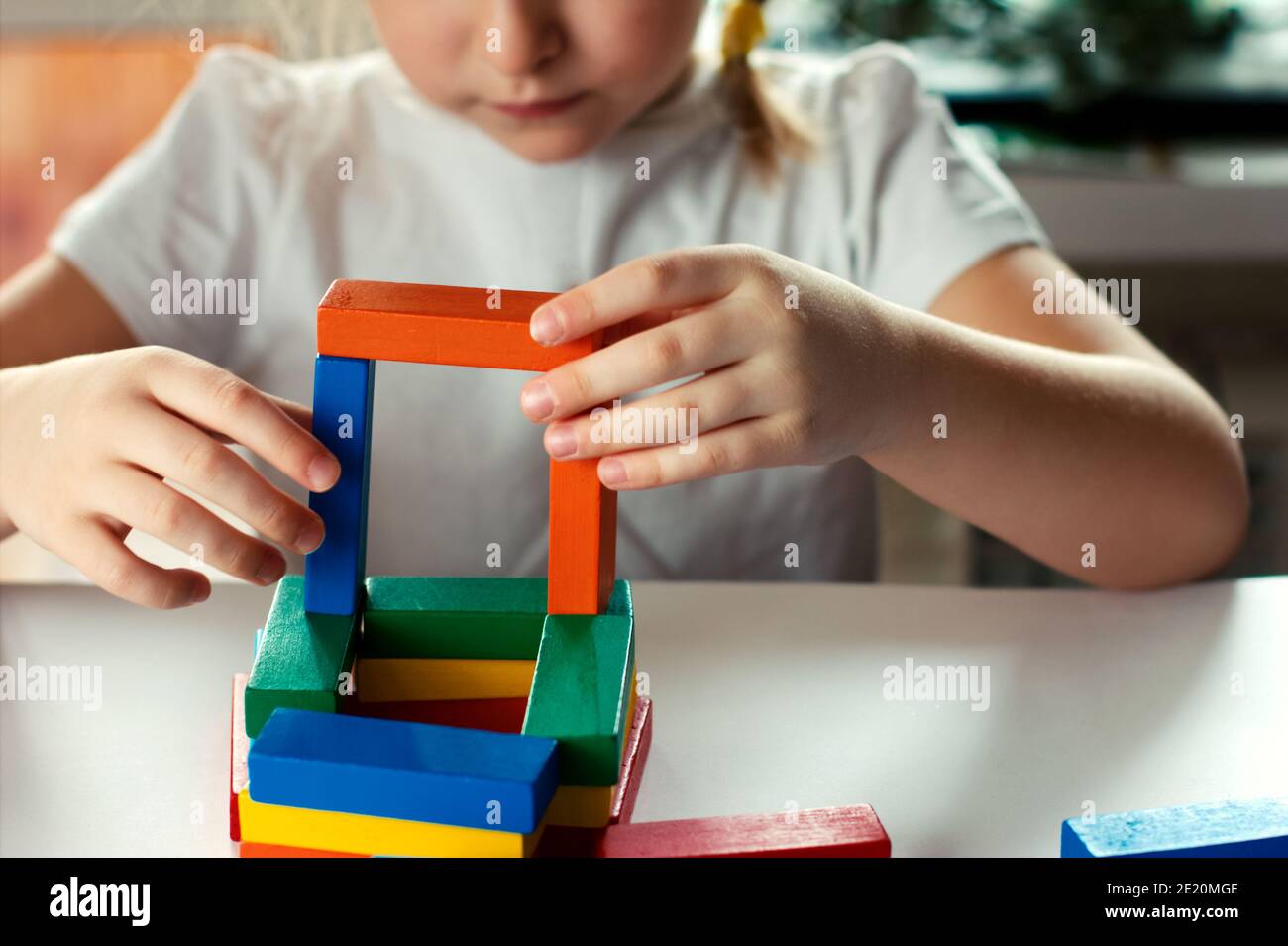 bambina bionda che gioca giochi da tavolo. concetto di giochi da tavolo.  blocchi di costruzione in legno nelle mani della ragazza. progetto per il  tempo libero dei bambini Foto stock - Alamy