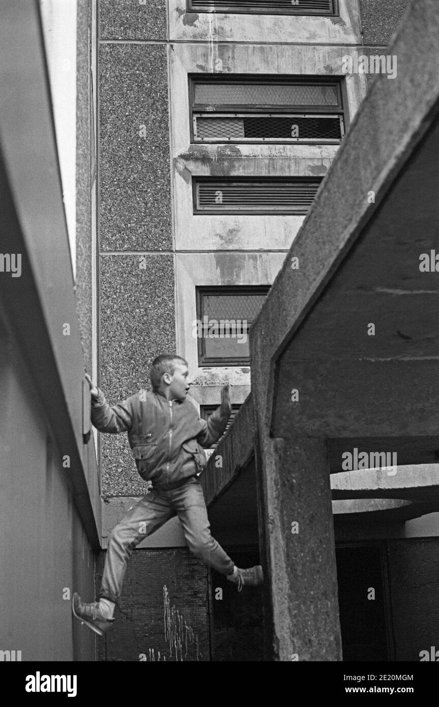 Boy climbing una tenda di un blocco torre, gennaio 1986, Ballymun, Dublino, Repubblica d'Irlanda Foto Stock