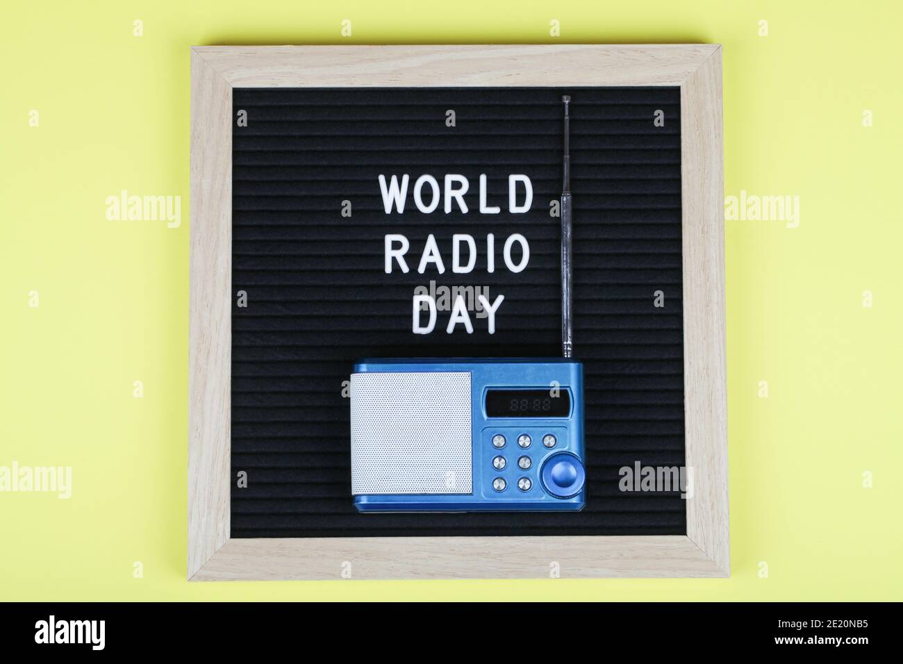 lavagna nera con testo mondo radio giorno con radio blu su sfondo giallo. Vista dall'alto. Disposizione piatta sfondo minimo. Foto Stock