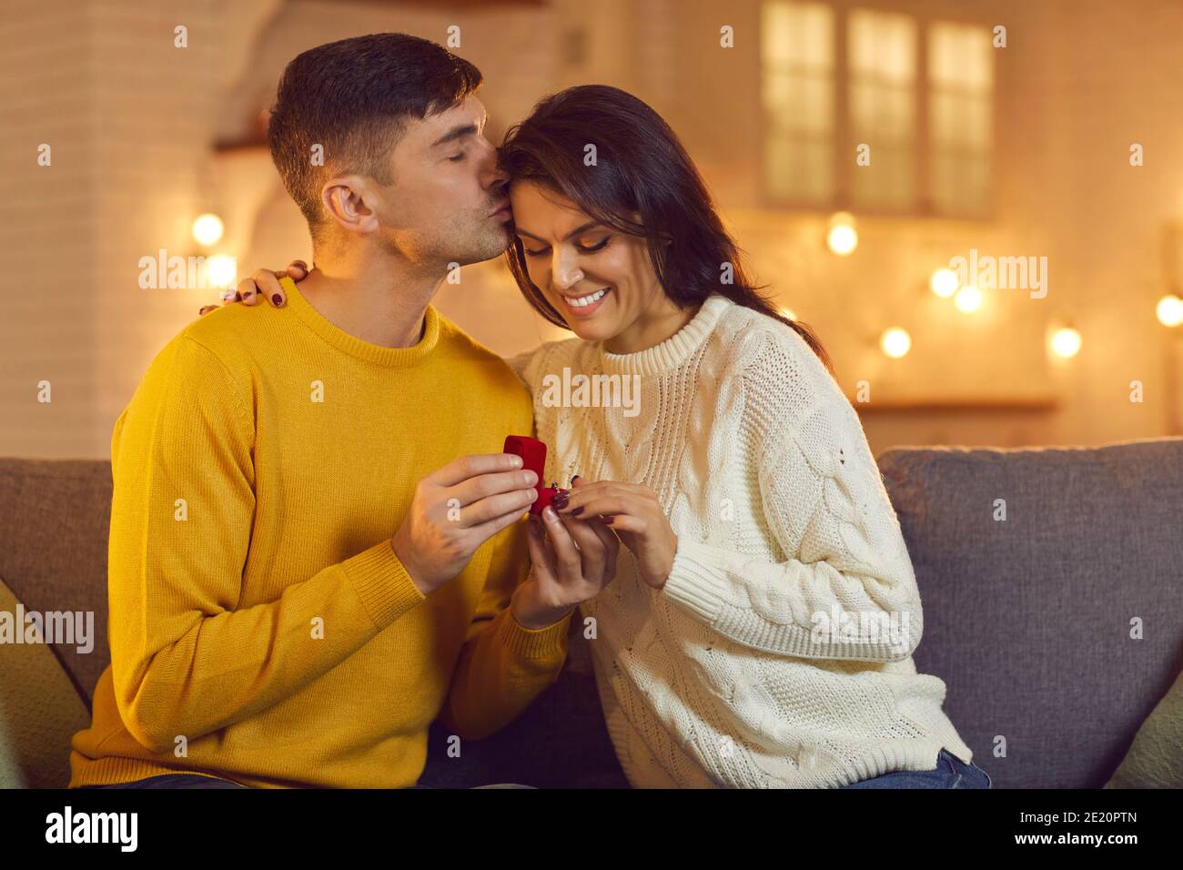 Giovane donna sorridente che riceve proposta con anello dal suo ragazzo Durante la festa di San Valentino Foto Stock