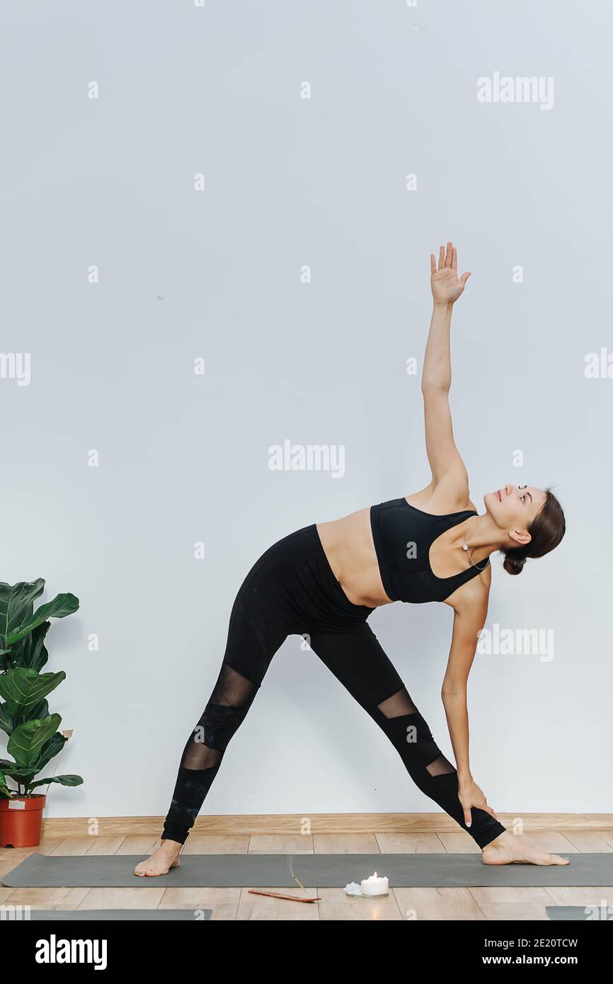 Donna flessibile che pratica yoga, facendo scivolare curva laterale su un tappetino nel centro benessere Foto Stock