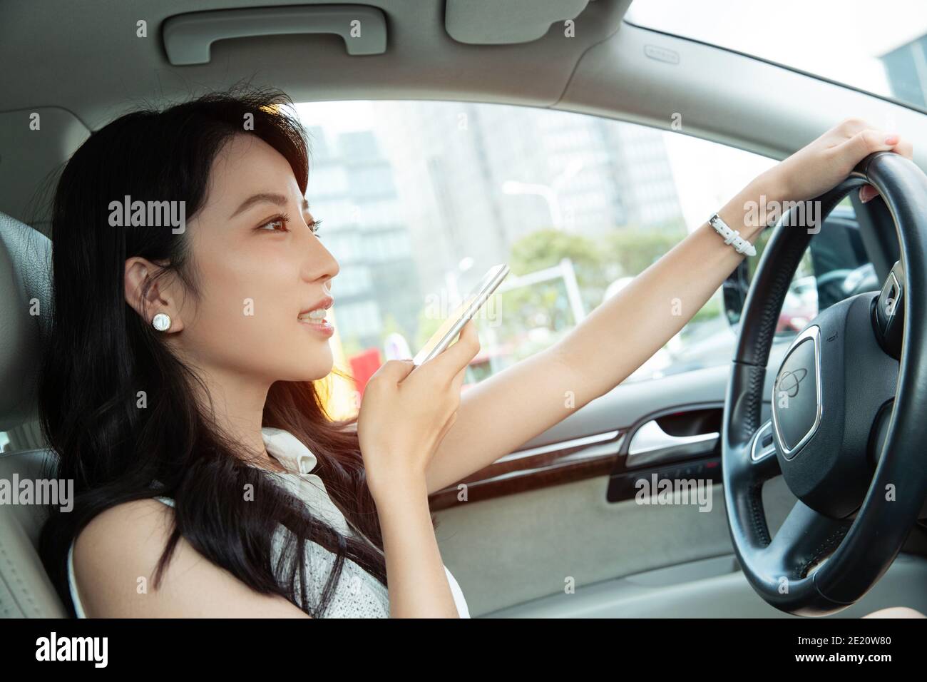 Giovane donna mentre guida la chat vocale Foto Stock