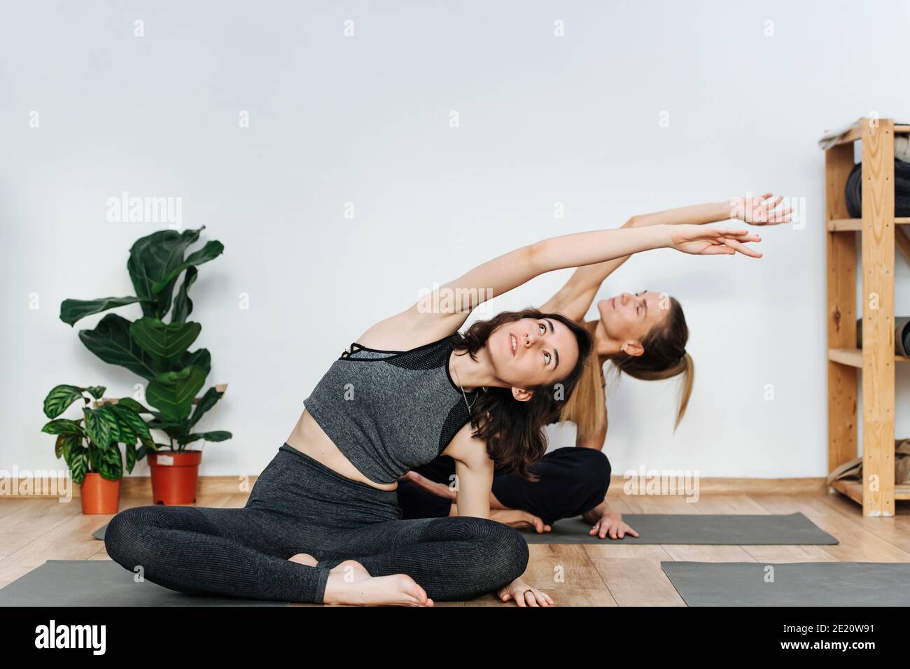 Donne immerse che praticano yoga facendo seduta laterale curva su un tappetino nel centro benessere Foto Stock