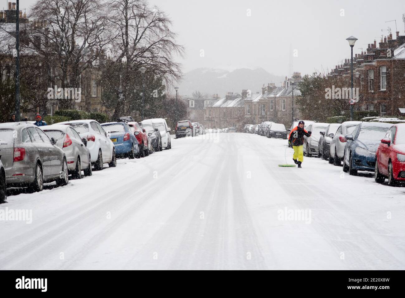 Un bambino che corre lungo una strada innevata di Edimburgo, Scozia, Regno Unito Foto Stock