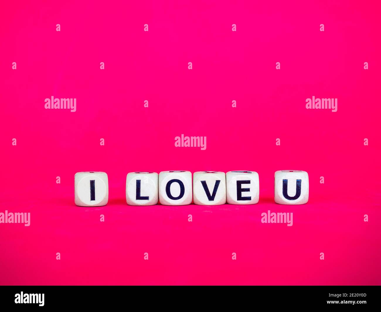 I Love U parola scritta su blocco di legno su sfondo rosa rosso con spazio di copia, stile minimal. Amore, il testo è scritto in lettere nere su cubi di legno. Foto Stock