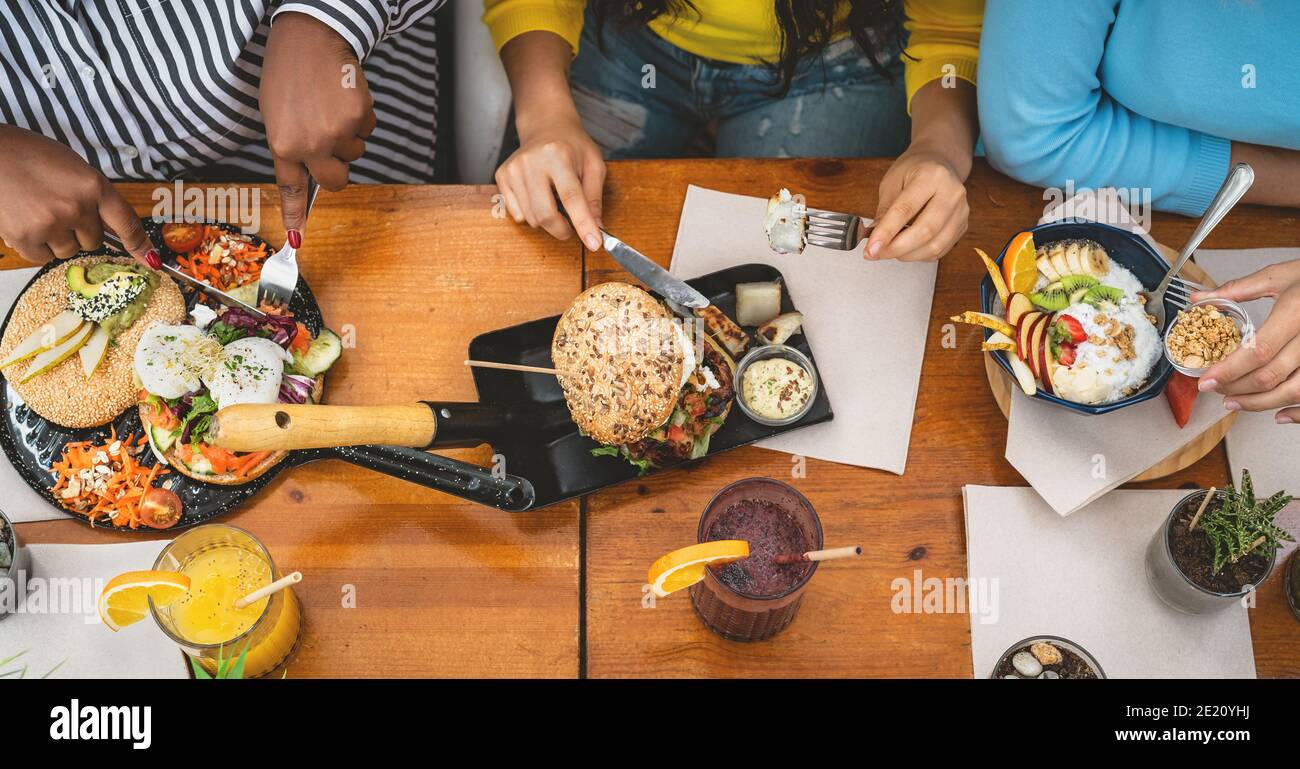 Vista dall'alto di amici multirazziali che hanno un pranzo sano nel caffè Brunch bar - stile di vita dei giovani e concetto di alimentazione Foto Stock