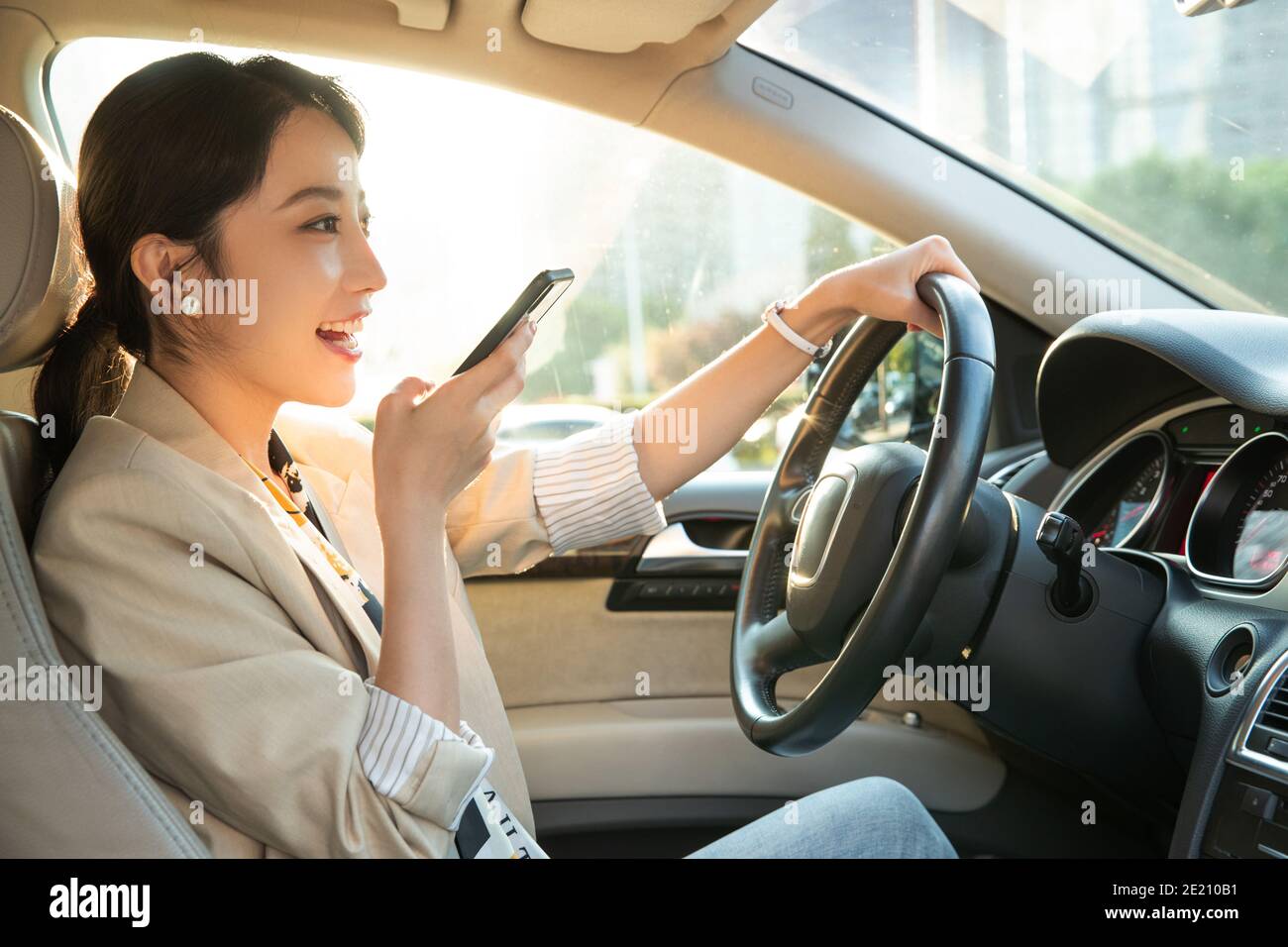 Giovane donna mentre guida la chat vocale Foto Stock