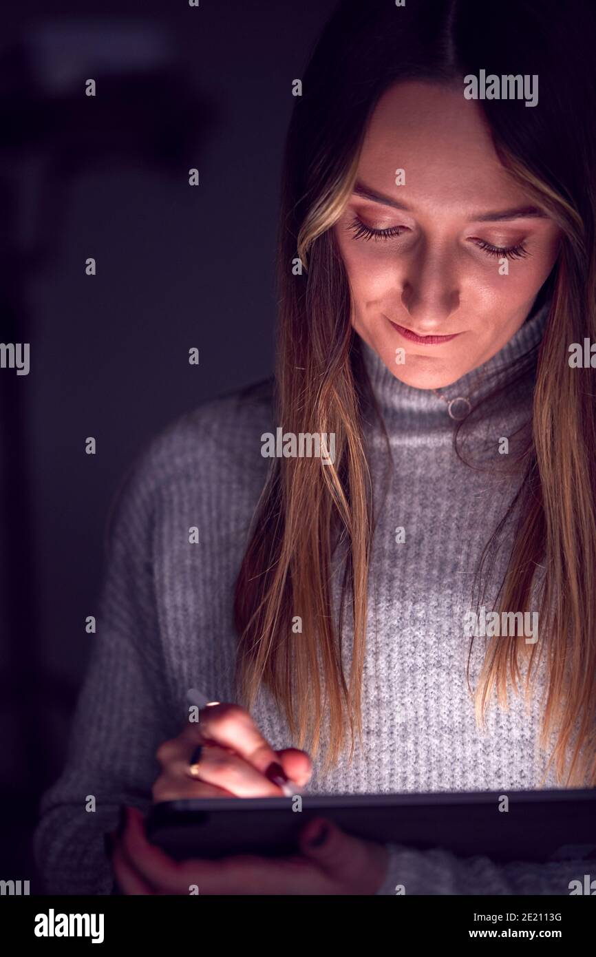 Donna d'affari che lavora in tarda mattinata disegno su tavoletta digitale usando la penna di Stylus Con volto illuminato Foto Stock