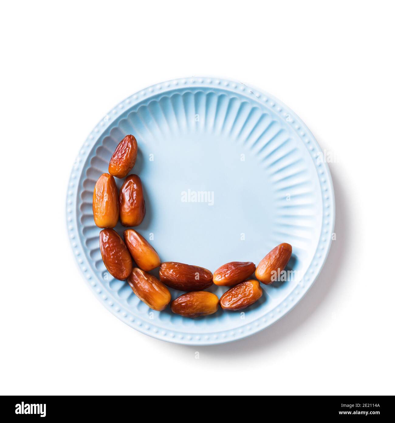 Mezzaluna islamica. Ramadan kareem con frutta datteri disposti a forma di luna crescente su piatto blu isolato su sfondo bianco, vista dall'alto, spazio copia Foto Stock