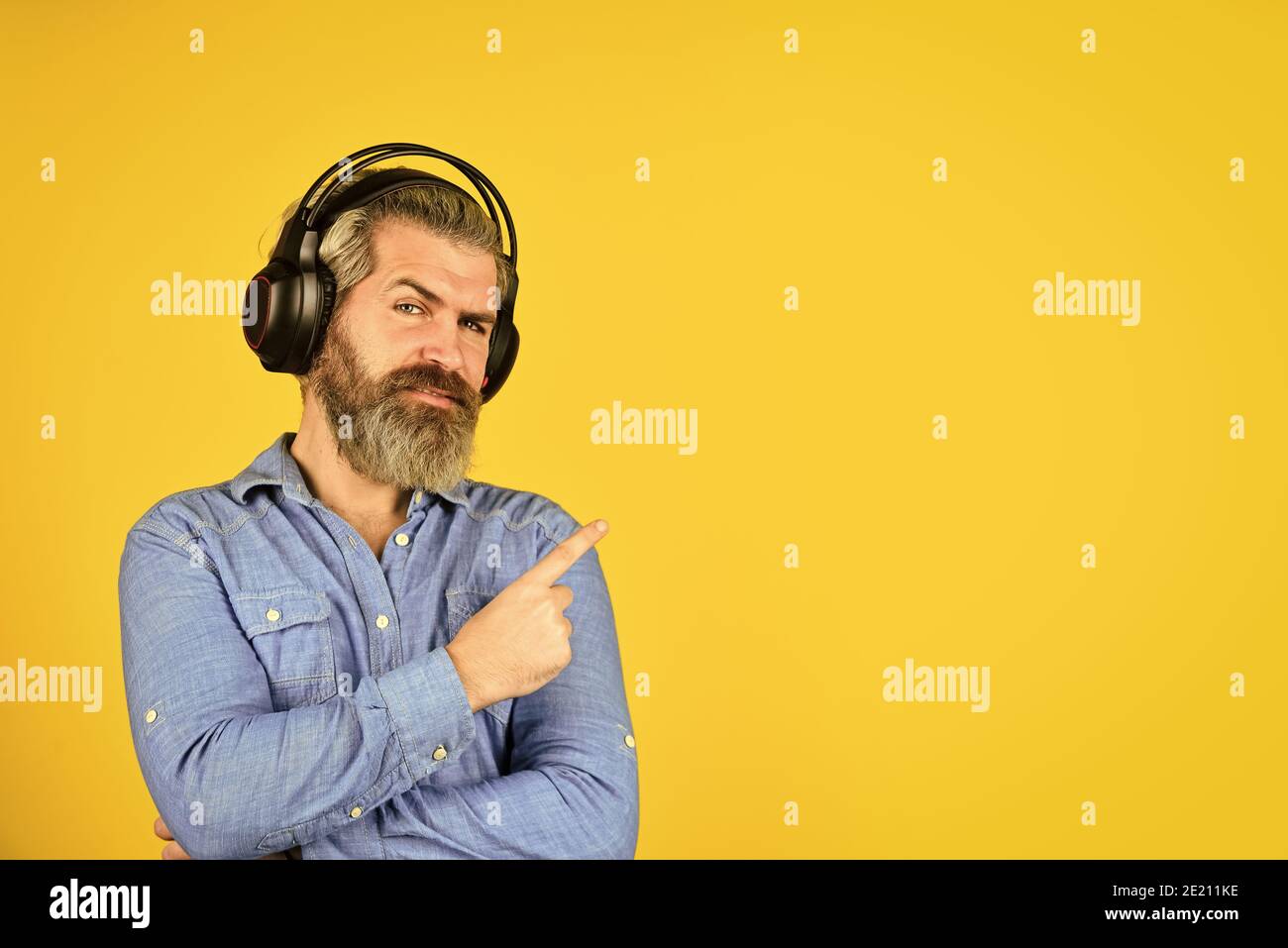 uomo bearded hipster che punta il dito, copia spce. ascolta audio libro. Musica per un umore energico. La sua canzone preferita. Goditi un'eccellente canzone audio con gli auricolari. Playlist Good Mood. Uomo con cuffia. Foto Stock