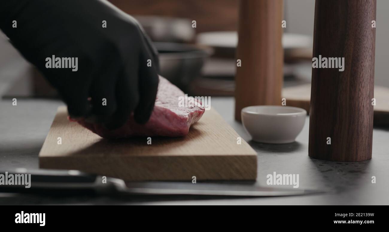 uomo mettere carne di manzo cruda su tavola di quercia, foto ampia Foto Stock