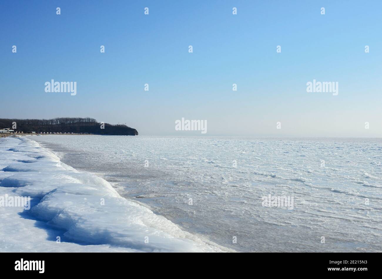 Spiaggia invernale ghiacciata con blocchi di ghiaccio ghiacciato sulla riva. Lazurnaya Bay, Vladivostok, Russia. Foto Stock