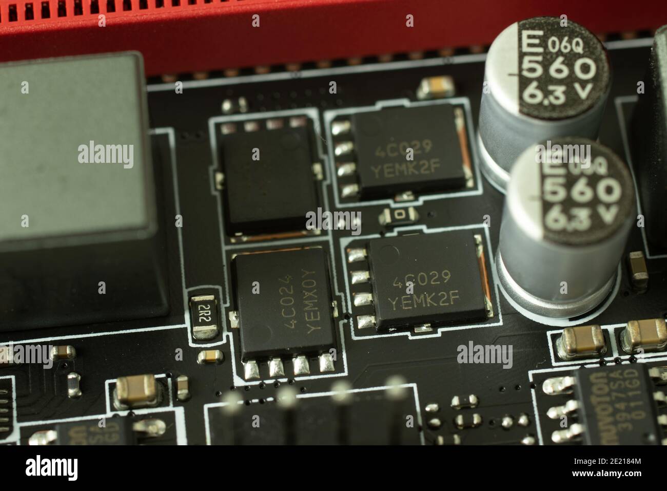 Primo piano di transistor, chip e altri elementi sul circuito elettrico della scheda madre. Foto Stock