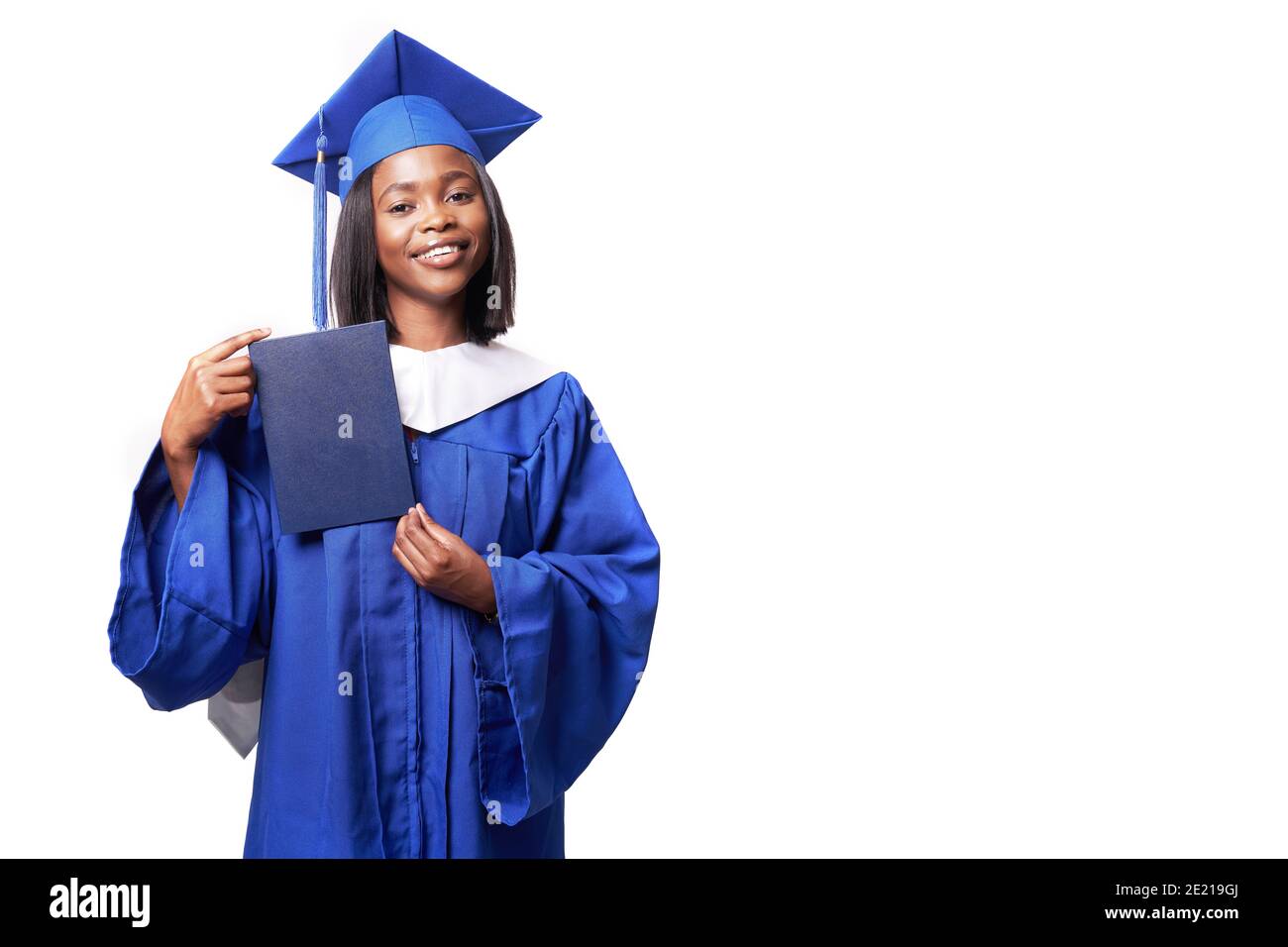 Afroamericana bella donna in una veste blu e cappello, su uno sfondo bianco isolato sorride e mostra diploma Foto Stock