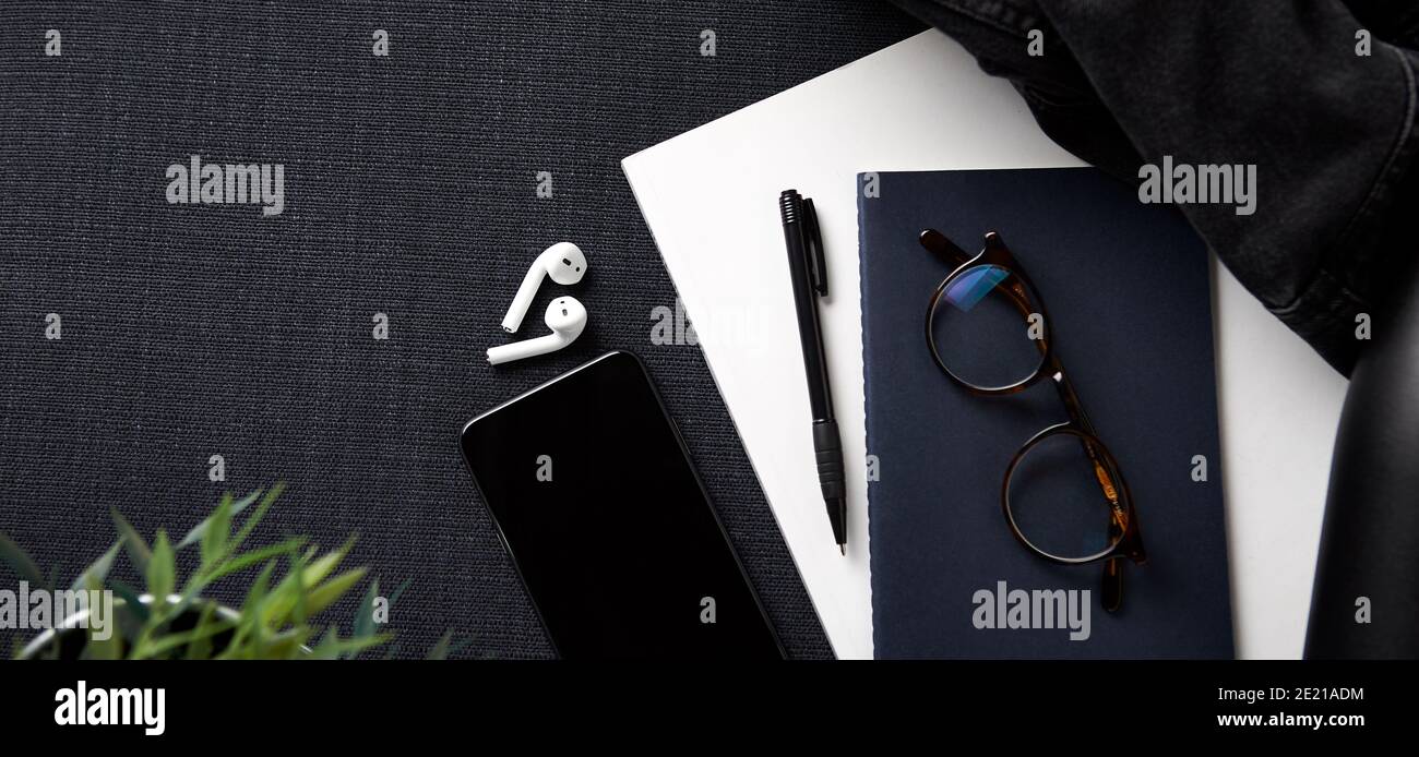 Flat Lay Lifestyle Shot con Jacket notebook cellulare e. Auricolari wireless su sfondo nero Foto Stock