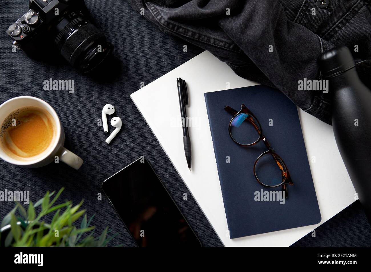 Flat Lay Lifestyle Shot con fotocamera giacca notebook cellulare E auricolari su sfondo nero Foto Stock