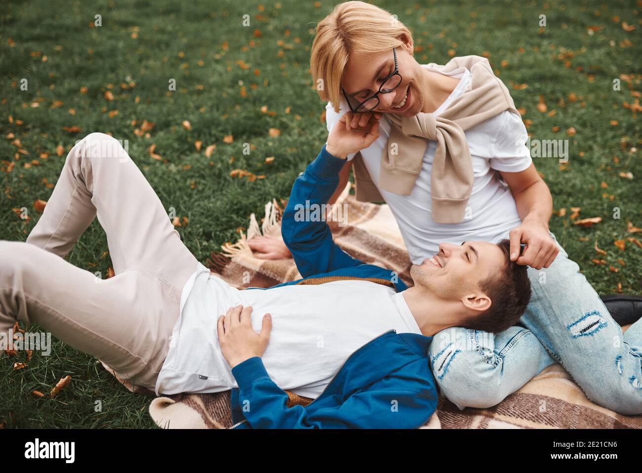 Coppia gay amorevole che ha date romantiche all'aperto. Due bei uomini seduti insieme sulla coperta nel parco. Concetto LGBT. Foto Stock