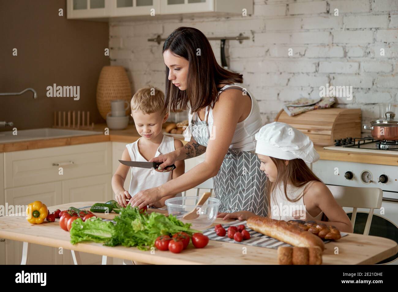 Mamma cucina pranzo con i bambini. Una donna insegna alla figlia di  cucinare dal figlio. Vegetarianismo e cibo naturale sano Foto stock - Alamy