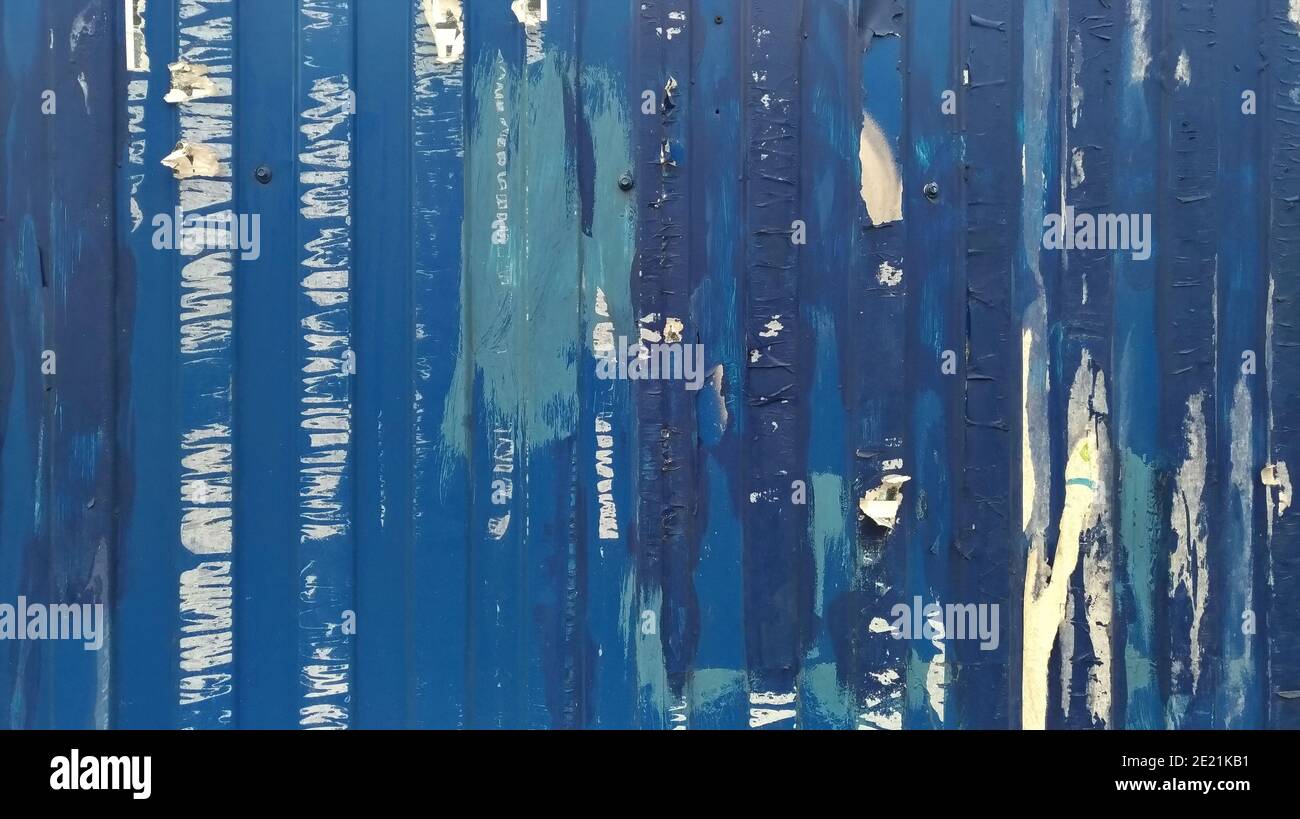 Una vecchia recinzione blu con tracce di annunci incollati Foto Stock