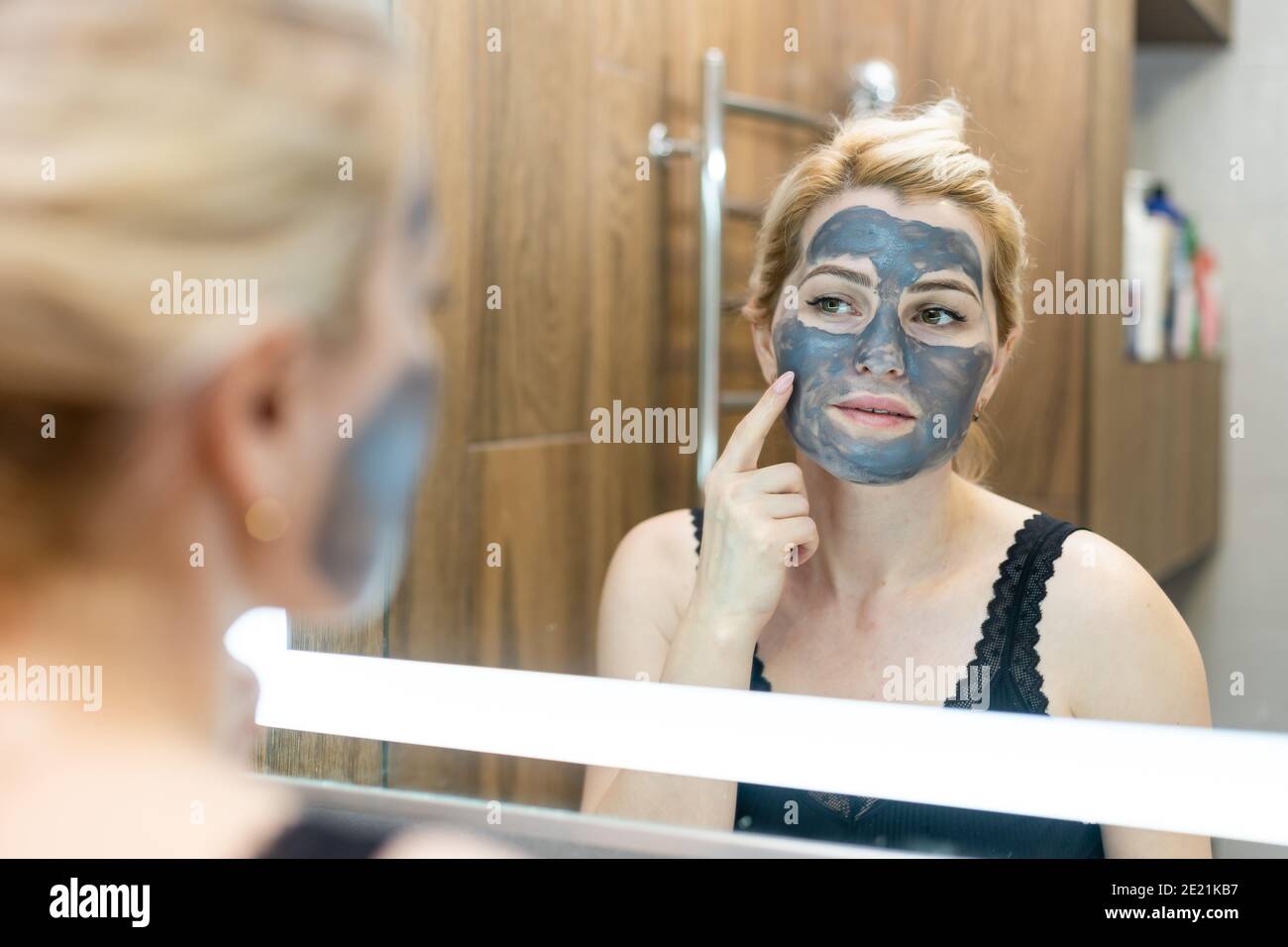 Giovane e bella donna con maschera nera a strappo sul viso dopo la doccia  Foto stock - Alamy