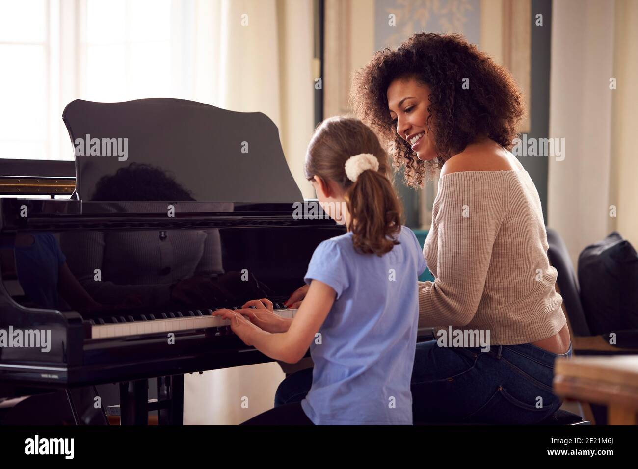 Giovane ragazza imparare a suonare piano avendo lezione da femmina Insegnante Foto Stock