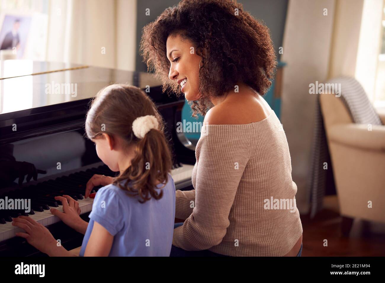 Giovane ragazza imparare a suonare piano avendo lezione da femmina Insegnante Foto Stock