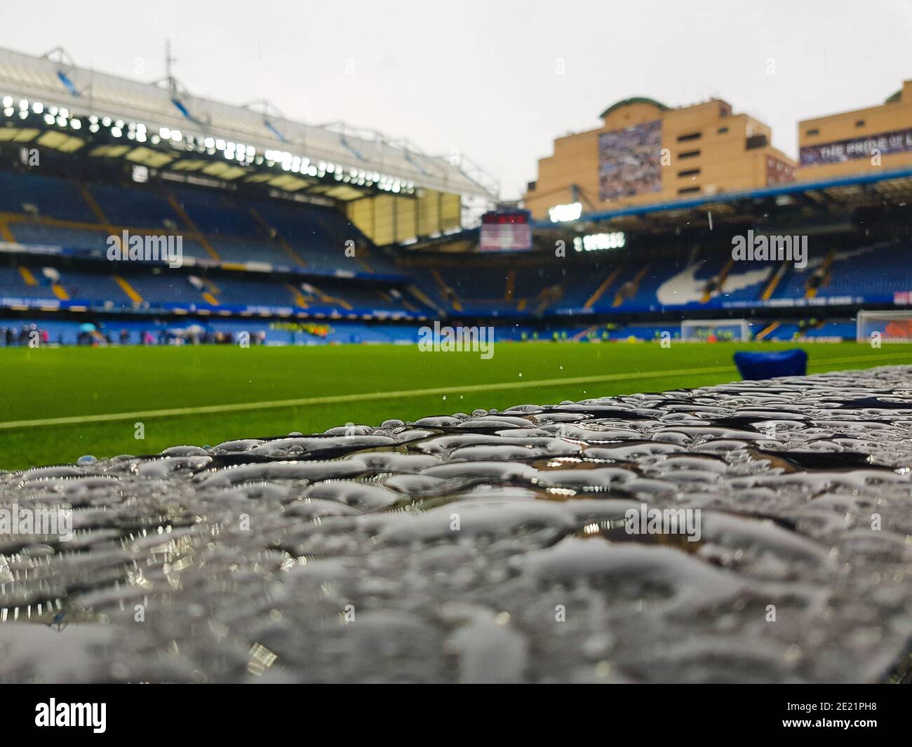 La pioggia cade in primo piano con una vista generale del Stadio Stamford Bridge del Chelsea FC Foto Stock
