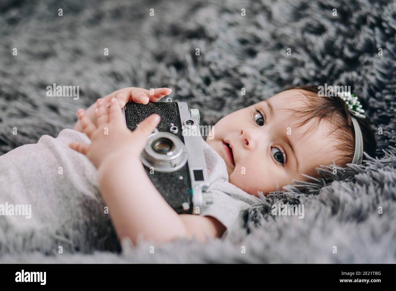 Closeup di carino, adorabile bambino che tiene reflex fotocamera vintage film Foto Stock
