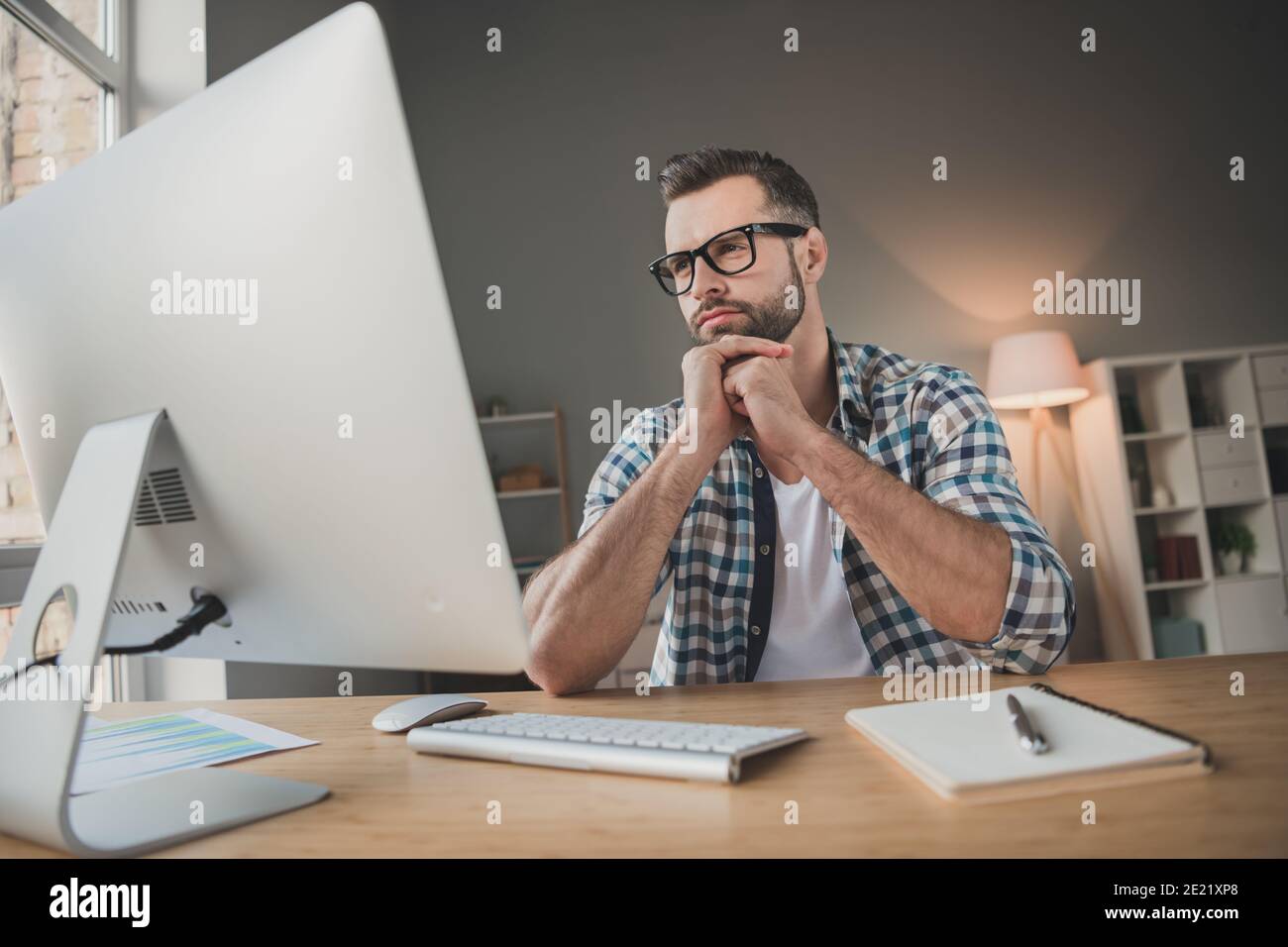 Foto di giovane bell'uomo serio concentrato guardare computer pensare il telecomando per il mento con le mani premurose può essere toccato a casa Foto Stock