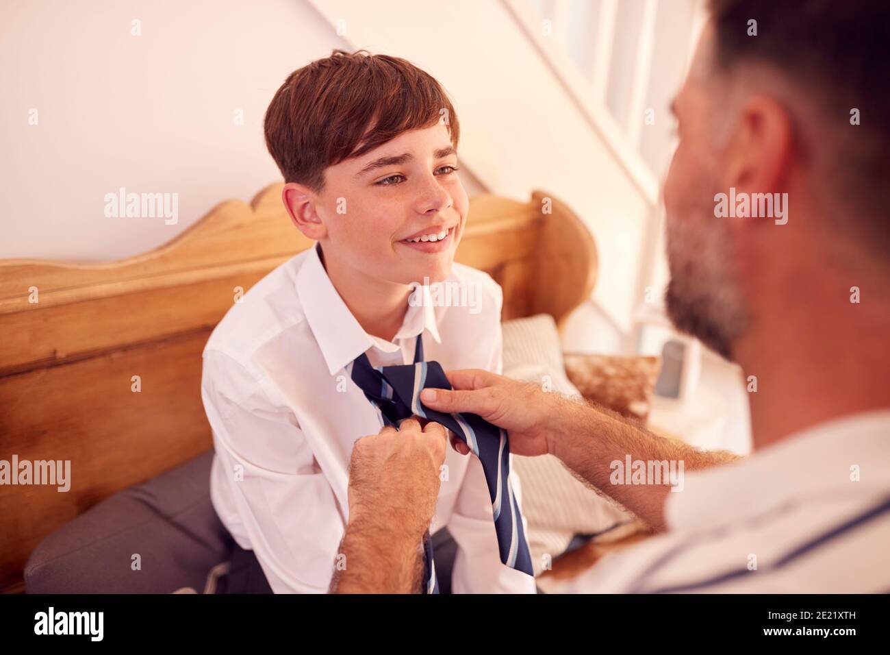 Padre che aiuta Son a legare Necktie prima che lasci la casa Per il primo giorno a High School Foto Stock
