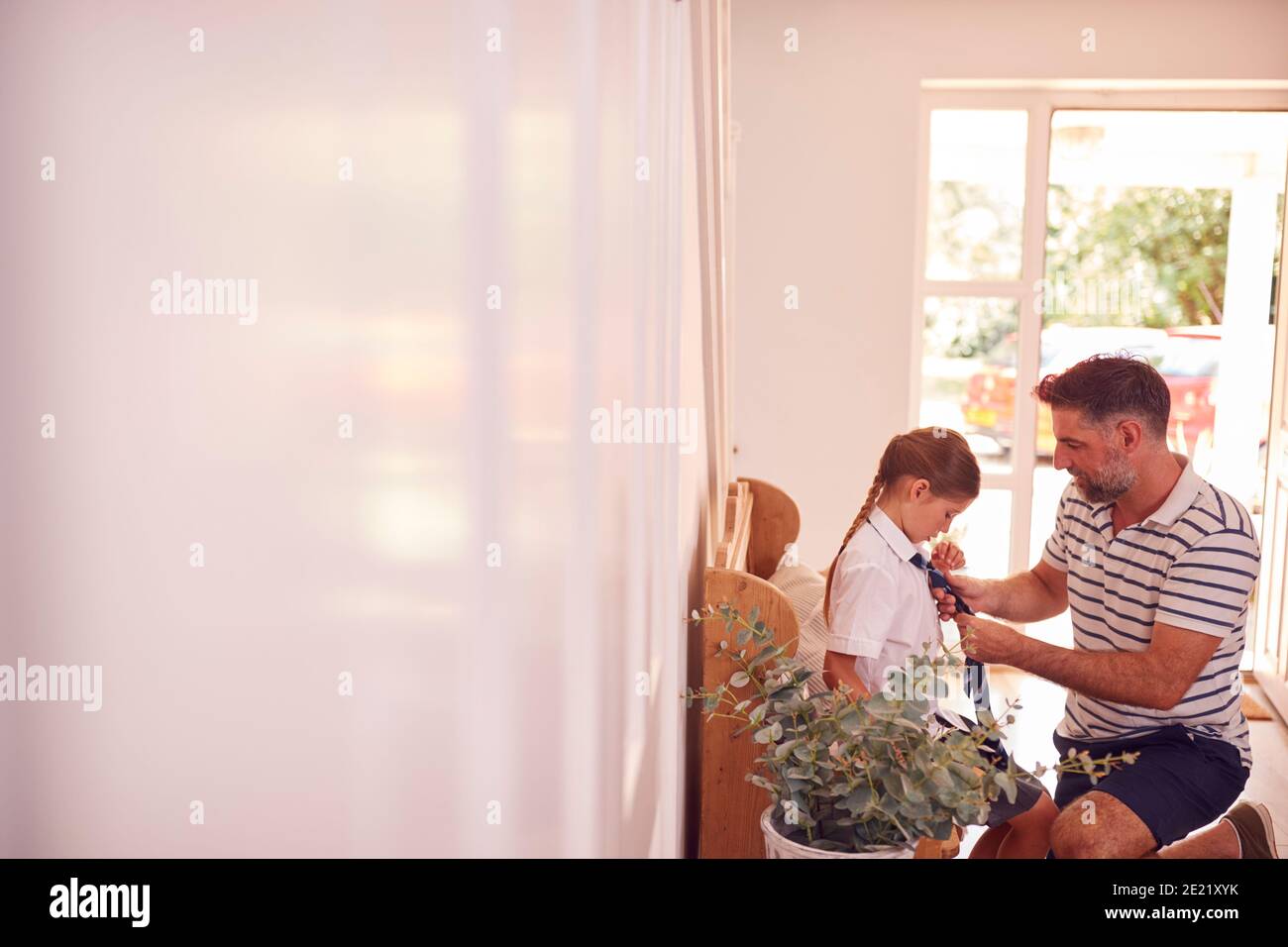 Padre che aiuta la figlia a Tie Necktie prima di lasciare casa Per il primo giorno alla scuola elementare Foto Stock