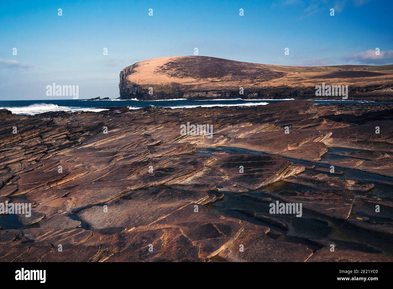 Roccia marrone sulla riva di Orkney con l'oceano Atlantico e scogliera in background un Foto Stock