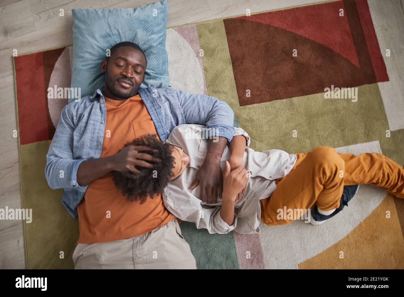 Dall'alto immagine di amorevole padre afroamericano rilassante sul pavimento a casa con suo figlio Foto Stock