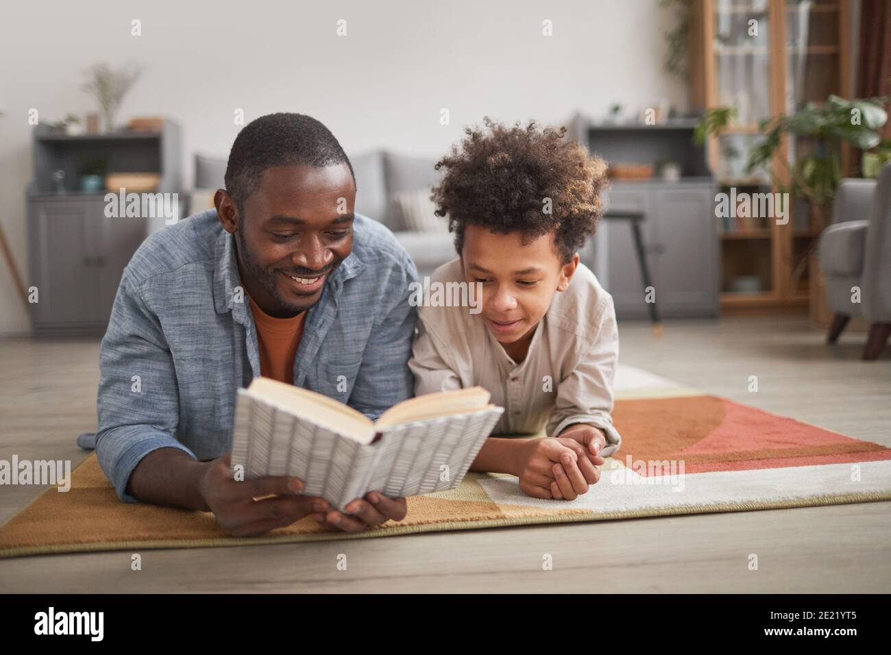 Felice padre trascorrere del tempo libero con il suo bambino che si rilassa a piano lettura interessante libro insieme Foto Stock