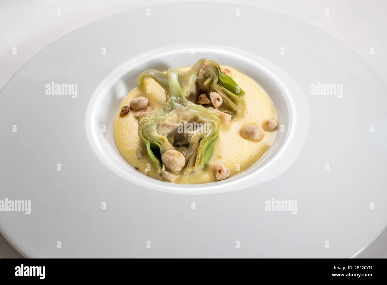 Carciofi alla fonduta di fontina con nocciole 'tonda gentile di Langaa', Piemonte, Italia in piatto bianco Foto Stock