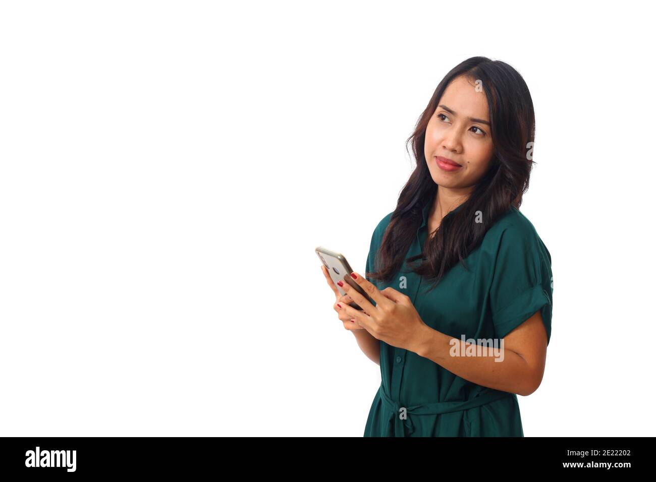 Ritratto di un felice asian imprenditrice tenendo il telefono cellulare e guardando lontano isolate su sfondo bianco Foto Stock