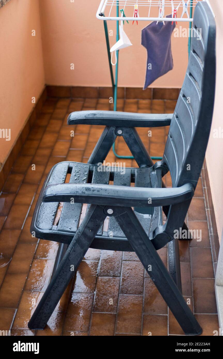 sedia verde bagnata nel piccolo balcone dell'appartamento dopo la pioggia Foto Stock