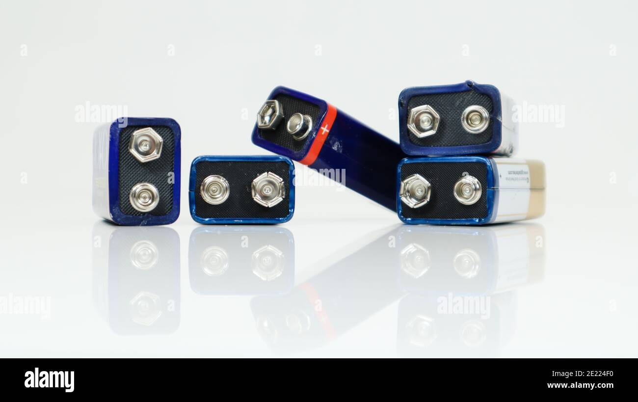 Cinque batterie PP3 usate, disposte in modo caotica e sparse su sfondo bianco con riflessi. Batteria principale per alimentatori personali. Clos Foto Stock