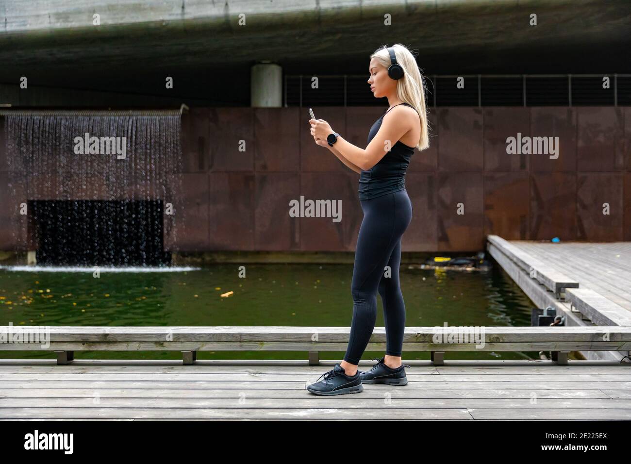 Donna runner prepara il monitoraggio delle prestazioni sullo smartphone prima di correre Foto Stock