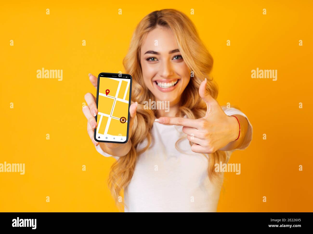 Cheerful Woman punta sullo smartphone con l'applicazione di navigazione GPS attivata Schermo Foto Stock
